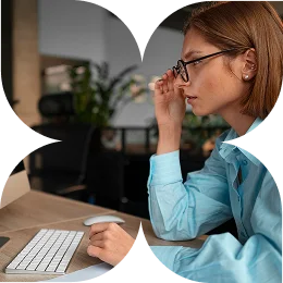 Woman in glasses pausing to think at her desk